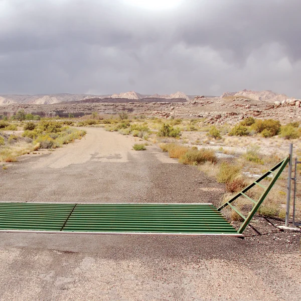 Powder River steel cattle guard installed across a ranch road, wings tied into the fence line